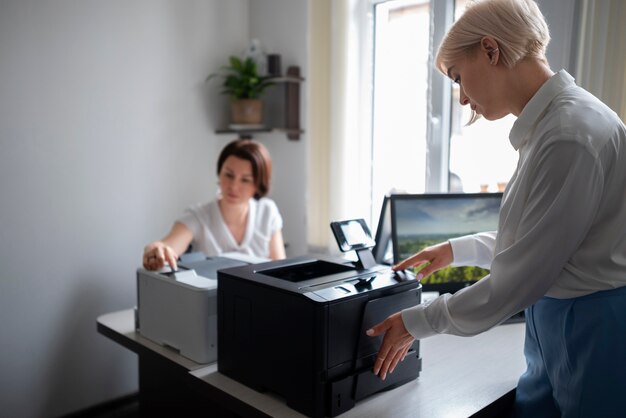 Mujeres en el trabajo en la oficina usando impresora