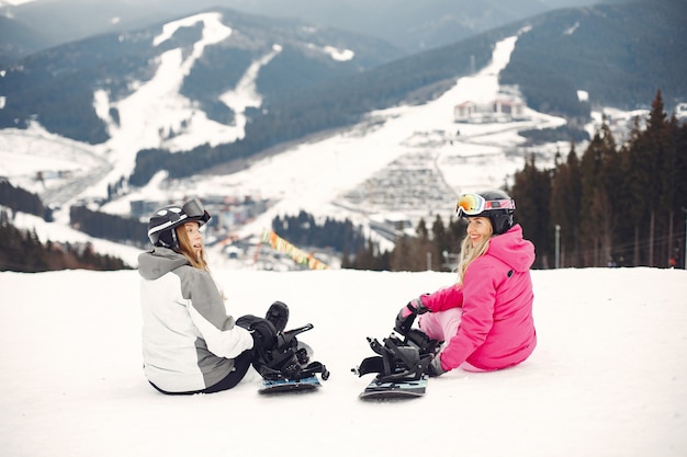 Foto gratuita mujeres en traje de snowboard. deportistas en una montaña con una tabla de snowboard en las manos en el horizonte. concepto de deportes