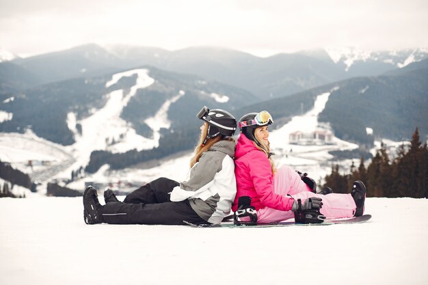 Mujeres en traje de snowboard. Deportistas en una montaña con una tabla de snowboard en las manos en el horizonte. Concepto de deportes