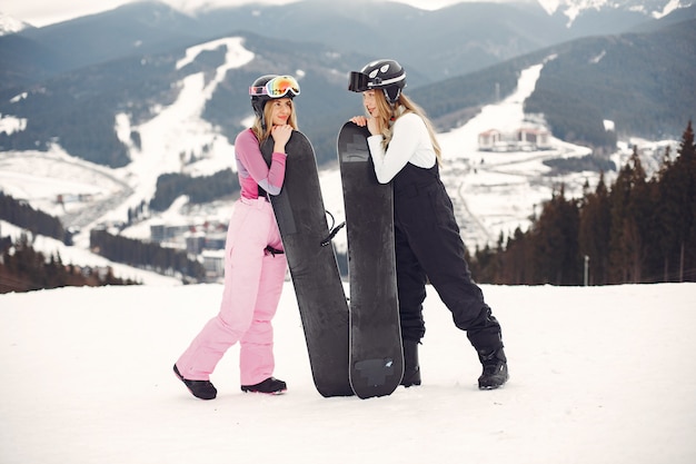 Mujeres en traje de snowboard. Deportistas en una montaña con una tabla de snowboard en las manos en el horizonte. Concepto de deportes