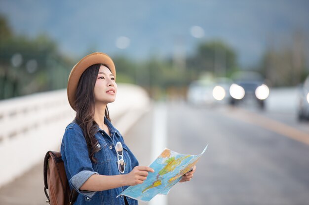 Mujeres turistas en mano tienen un feliz mapa de viaje.