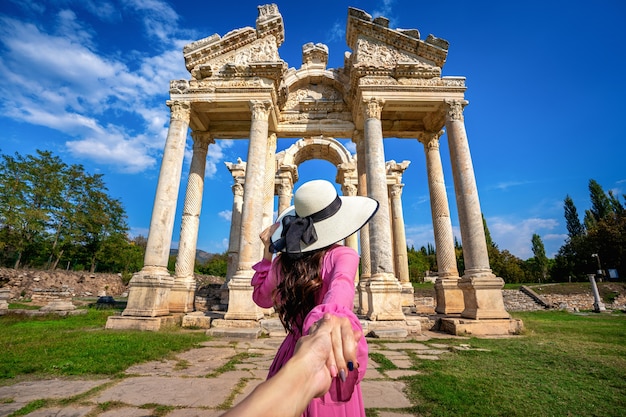 Foto gratuita las mujeres turistas que sostienen la mano del hombre y lo llevan a la antigua ciudad de afrodisia en turquía.