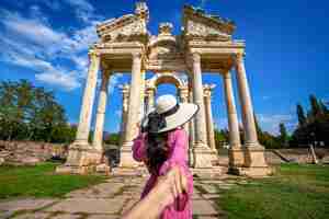 Foto gratuita las mujeres turistas que sostienen la mano del hombre y lo llevan a la antigua ciudad de afrodisia en turquía.