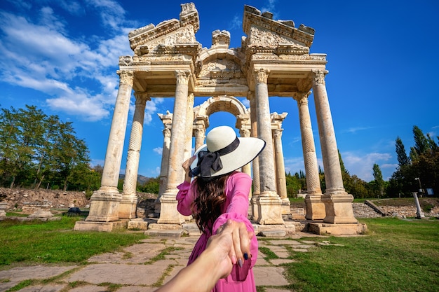 Las mujeres turistas que sostienen la mano del hombre y lo llevan a la antigua ciudad de Afrodisia en Turquía.