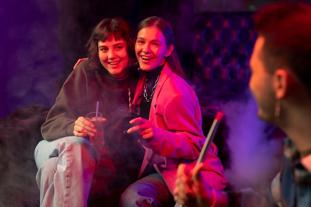 Foto gratuita mujeres vapeando desde una pipa de agua en interiores