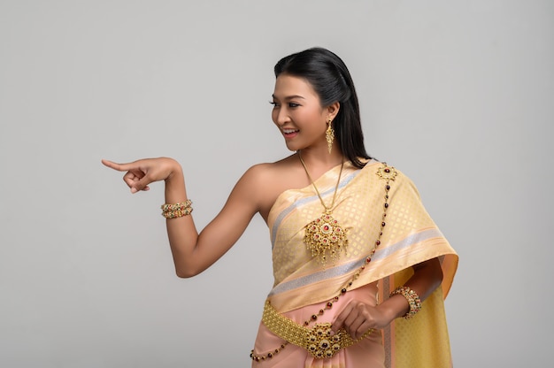 Mujeres vestidas con trajes tailandeses que son simbólicos, señalando con el dedo