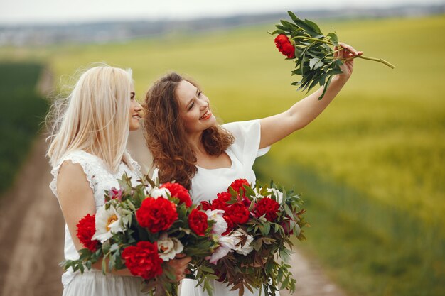 Mujeres en vestido elegante de pie en un campo de verano