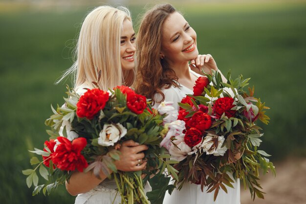 Mujeres en vestido elegante de pie en un campo de verano