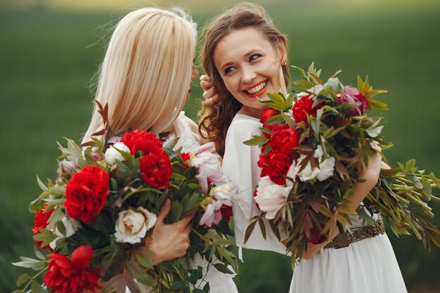 Mujeres en vestido elegante de pie en un campo de verano