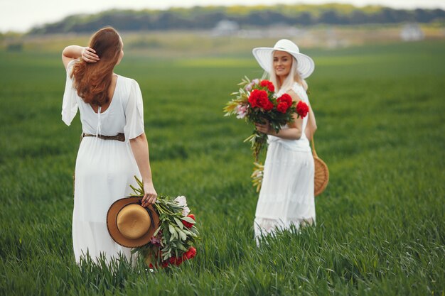 Mujeres en vestido elegante de pie en un campo de verano