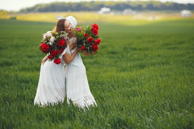 Mujeres en vestido elegante de pie en un campo de verano