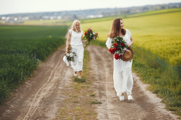 Mujeres en vestido elegante de pie en un campo de verano