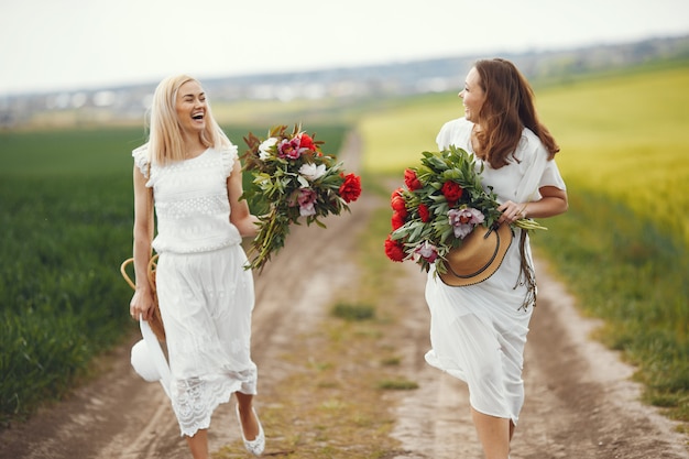 Mujeres en vestido elegante de pie en un campo de verano