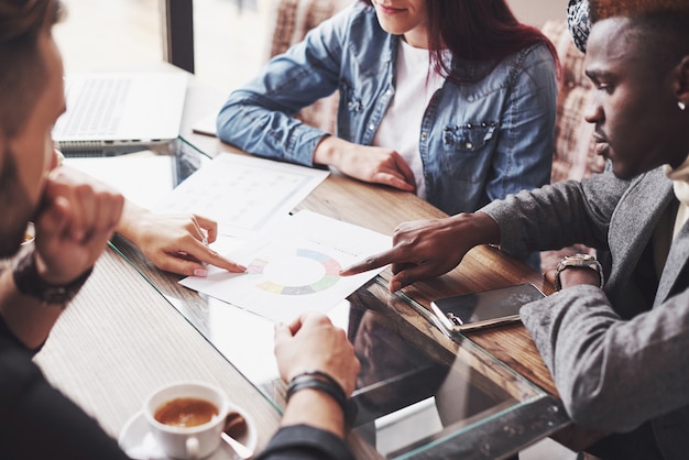 Multiétnico empresario de personas, concepto de pequeña empresa. Mujer mostrando a sus compañeros de trabajo algo en la computadora portátil mientras se reúnen alrededor de una mesa de conferencias