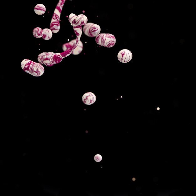 Múltiples bolas de acrílico abstractas en agua sobre fondo negro