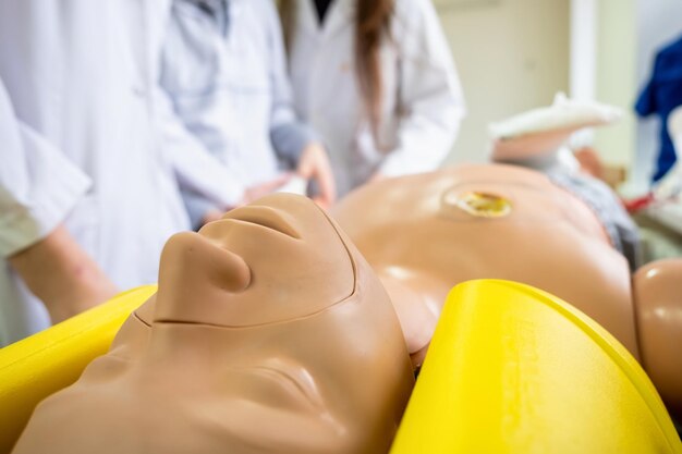 Muñeca de práctica médica para emergencias y estudiantes de medicina cerca de ella aprendiendo tipos de emergencias