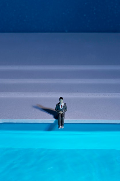 Muñeco hombre sentado junto a la piscina