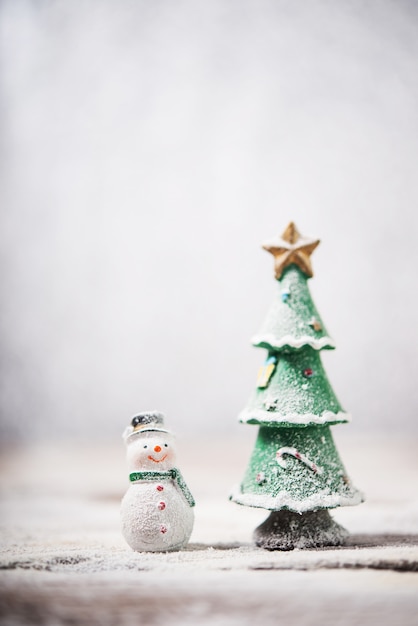 Muñeco de nieve junto a un árbol de navidad