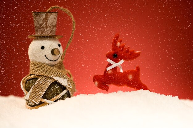 Muñeco de nieve y renos con el fondo rojo