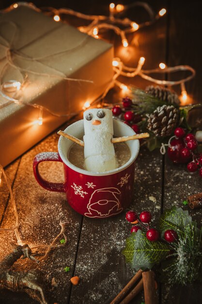 Muñeco de nieve en la taza de café en la mesa de navidad