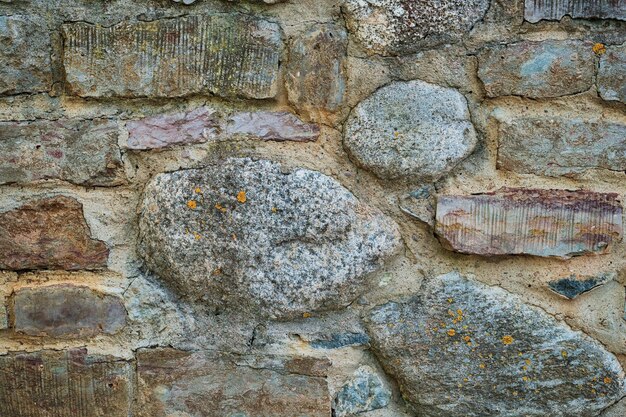 Muro de piedra gris hecho de piedras de textura de fondo de piedra áspera cruda de diferentes tamaños Idea para el diseño de la fachada de la casa o el edificio y el espacio público