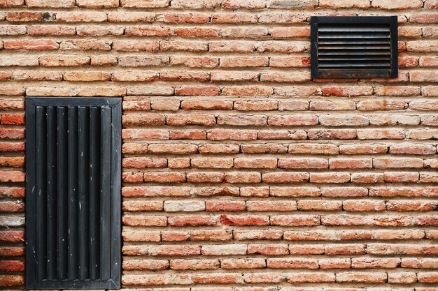 Muro de presa de ladrillo con rejillas de ventilación fondo publicitario o salvapantallas de papel tapiz