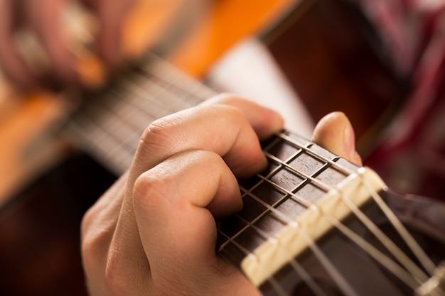 Música, primer plano. Músico sosteniendo una guitarra de madera