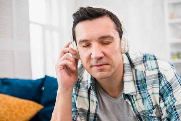 Foto gratuita música que escucha del hombre en auriculares en el sofá