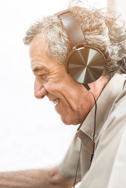 Foto gratuita música que escucha del hombre mayor en el auricular contra el fondo blanco