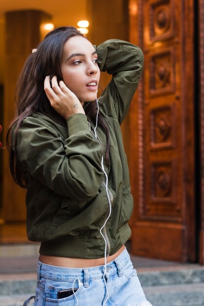 Foto gratuita música que escucha de moda de la mujer joven en el auricular