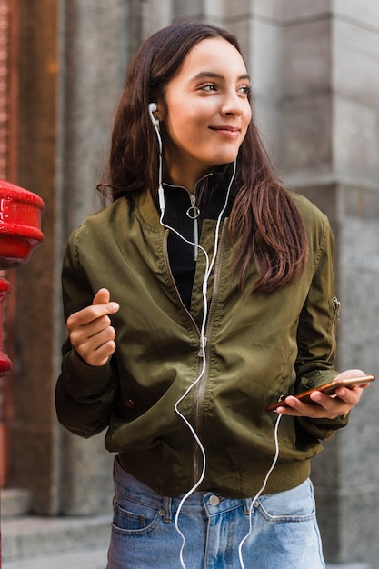 Foto gratuita música que escucha de la mujer joven en la fijación del auricular al teléfono móvil