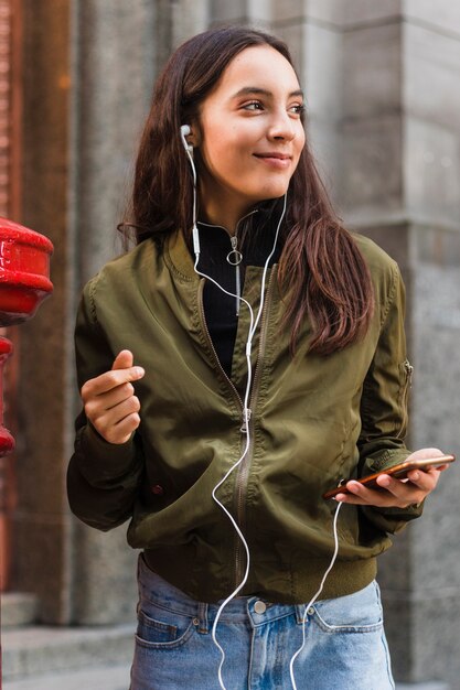 Música que escucha de la mujer joven en la fijación del auricular al teléfono móvil