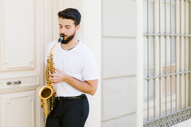 Músico apoyado contra la pared tocando el saxofón