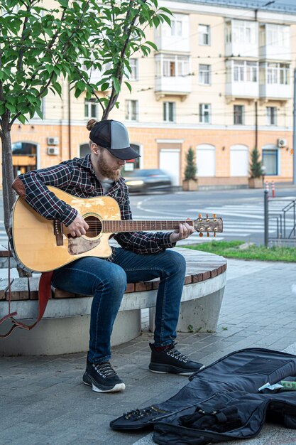 Músico callejero masculino toca la guitarra acústica