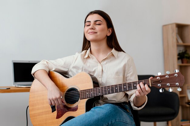 Músico femenino sonriente tocando la guitarra acústica