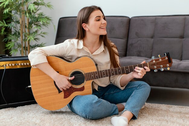 Músico femenino sonriente tocando la guitarra acústica