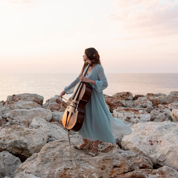 Músico femenino con violonchelo al aire libre