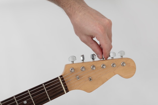 Músico masculino afinando una guitarra eléctrica