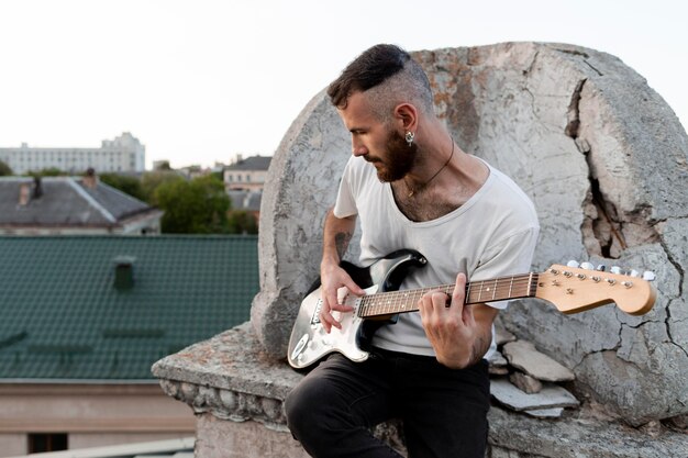 Músico masculino en la azotea tocando la guitarra eléctrica