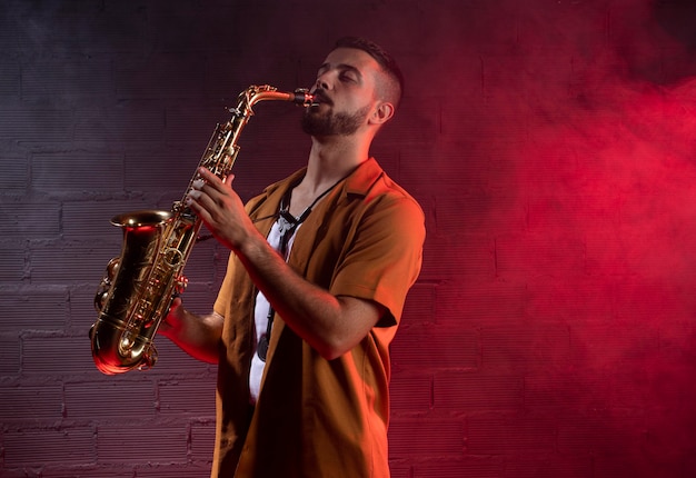 Foto gratuita músico masculino en la niebla tocando el saxofón