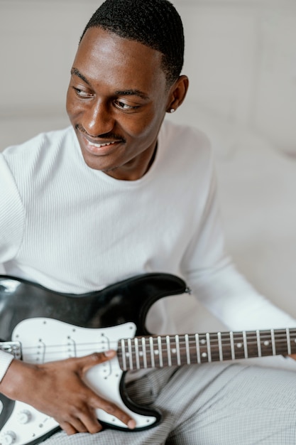 Músico masculino sonriente con guitarra eléctrica
