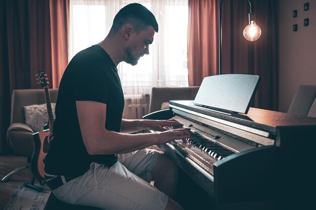 Músico masculino toca el piano electrónico en la habitación