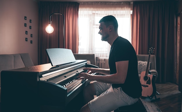 Músico masculino toca el piano electrónico en la habitación