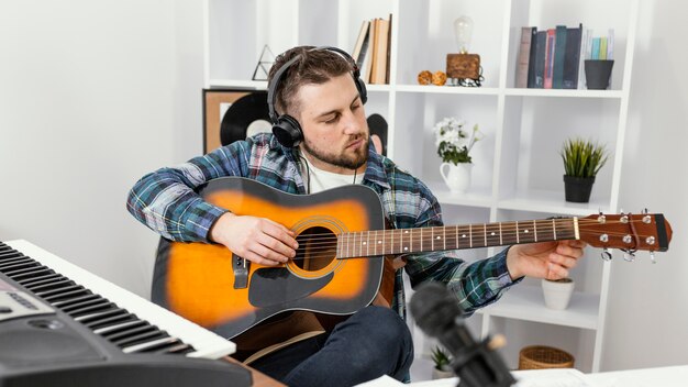 Músico de tiro medio tocando la guitarra