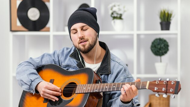 Músico de tiro medio tocando la guitarra