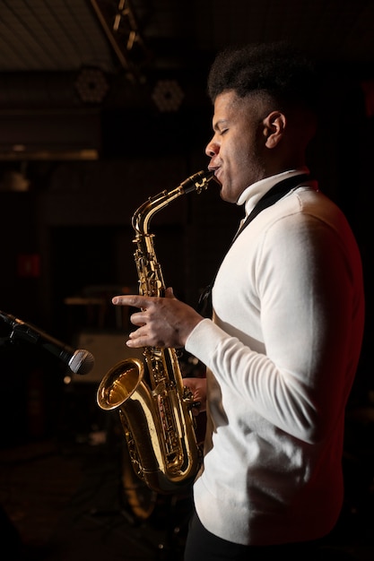 Foto gratuita músico de tiro medio tocando el saxofón.