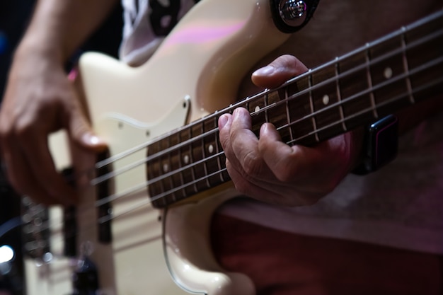 Músico tocando el bajo blanco de cerca.