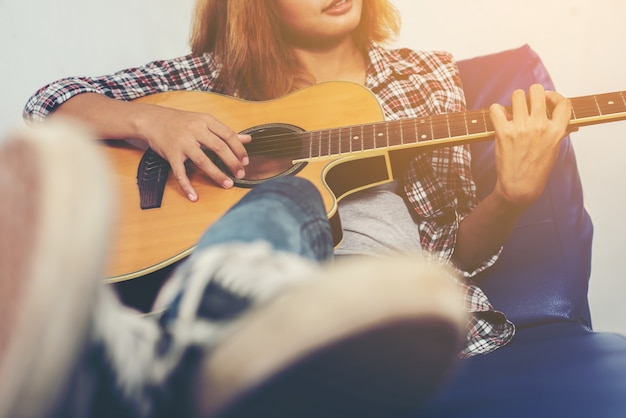 Músico tocando la guitarra en un sofá