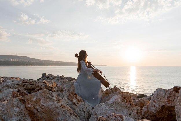 Músico tocando el violonchelo al aire libre al atardecer