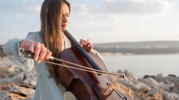 Músico tocando el violonchelo al atardecer con espacio de copia